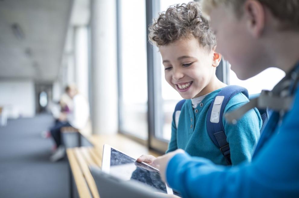  kinderen in een schoolgang met rugzak en tablet